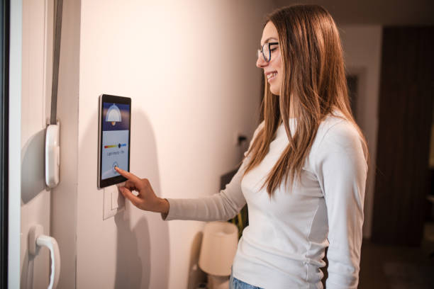 istock Young woman controlling home light son smart home app on device attached on wall 2196059656