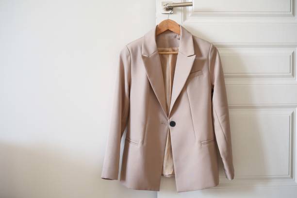 istock An elegant beige tailored blazer is beautifully is on a hanger against a clean white backdrop. 2196060325