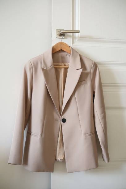 istock An elegant beige tailored blazer is beautifully is on a hanger against a clean white backdrop. 2196060379