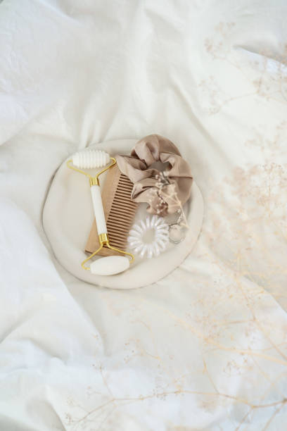 istock Essential Hair Care Items A Scrunchie, Roller, and Comb Displayed on Soft White Fabric 2196060432