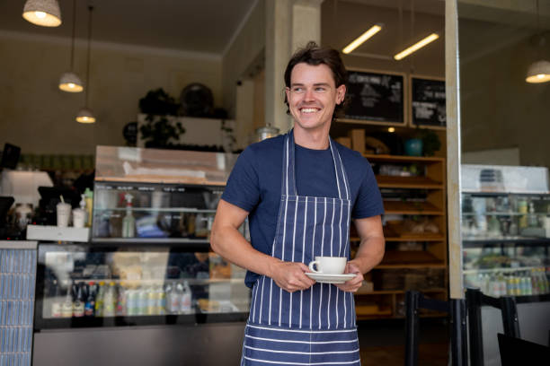 istock Waiter working at a cafe serving coffee and smiling 2196060871