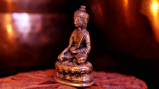 istock Small copper Buddha Statue in profile glowing in candlelight 2196063741