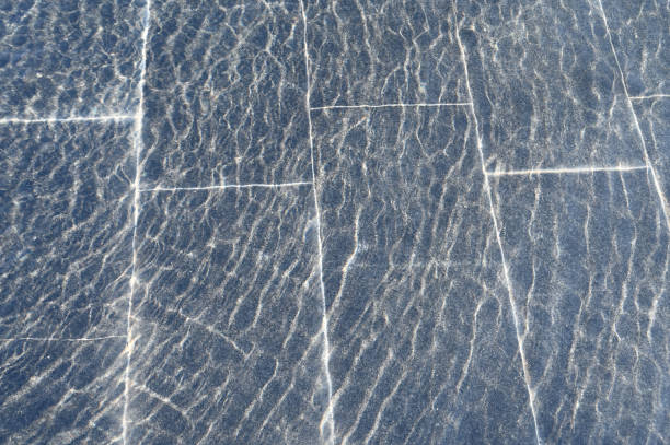 istock A thin layer of water with ripples on dark marble fountain tiles, illuminated by sunlight. 2196064953