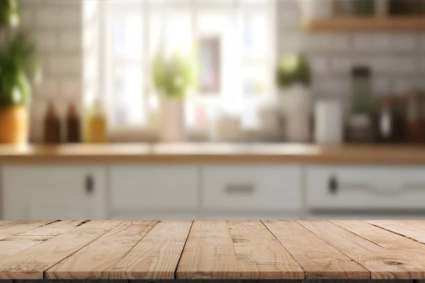 istock A kitchen interior, focusing on a wooden table or countertop in the foreground. The table has a natural wood finish with visible grain patterns. The ambiance is warm and inviting. 2196065256