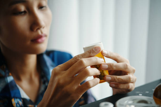 istock Asian Woman Choosing Pills To Take 2196067637
