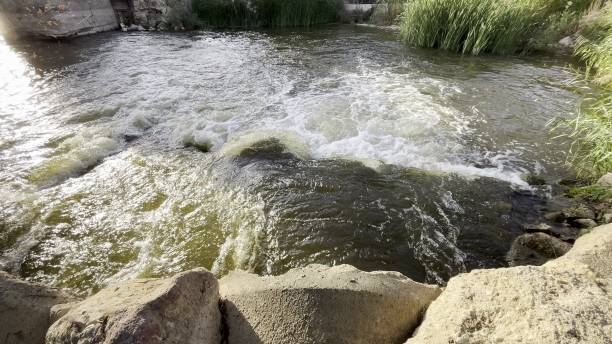 istock River water flowing over concrete and rock dam, creating whitewater rapids 2196069973
