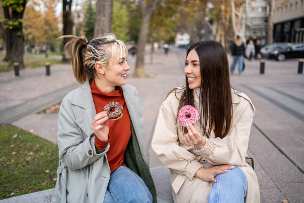istock Female friends enjoying eating donuts 2196071994