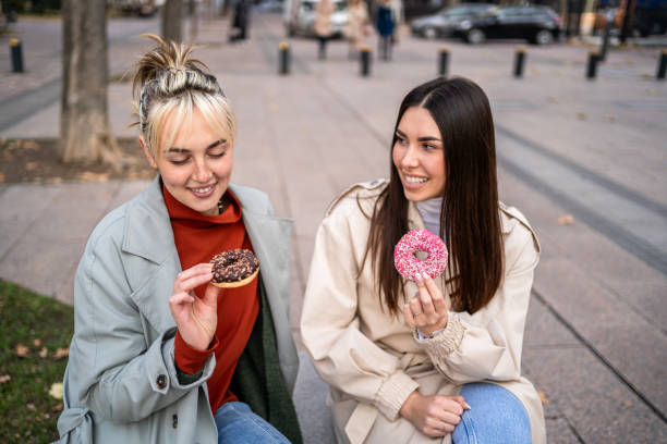 istock Female friends enjoying eating donuts 2196072029