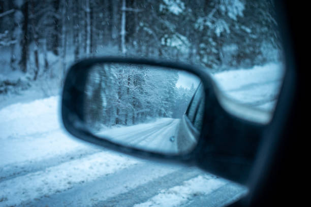 istock Reflection of car side view mirror on snowy forest road 2196072899