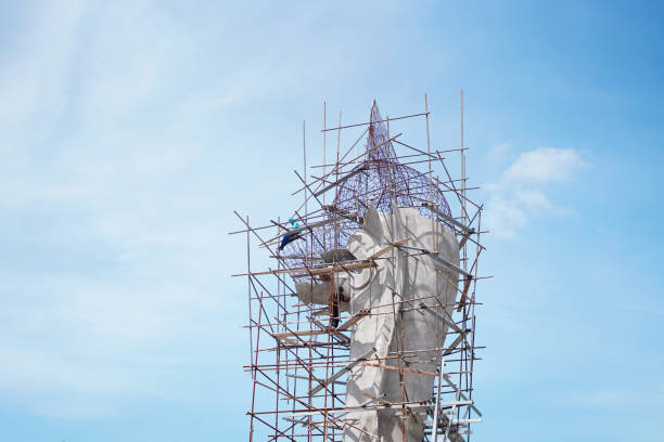 Two construction worker working on steel scaffold for build the big Serpent statue on sky background.Traditional Buddhist in Thailand.