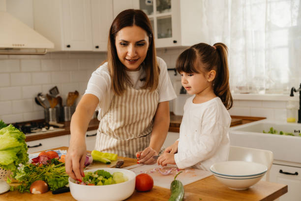 istock Mother and daughter making salad together 2196073691
