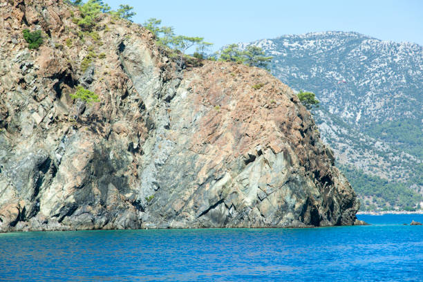 The scenic view of steep rocky coastline with Adrasan tourist town in a background in Antalya province (Turkey).