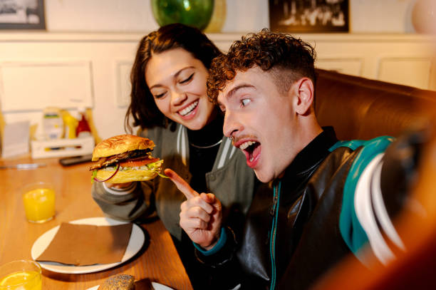 istock Young couple taking a selfie while enjoying burgers at restaurant 2196076014