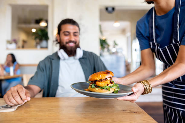 istock Waiter serving a burger to a customer at a restaurant 2196076676