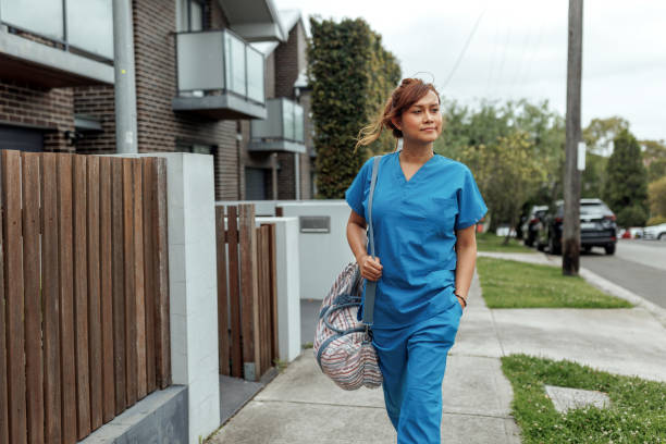 istock Female nurse walking on sidewalk, she is carrying a bag 2196078705