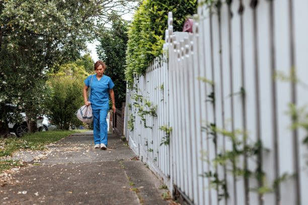 istock Female nurse walking on sidewalk, she is carrying a bag 2196078782