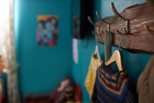 Selective focus of sweaters on hangers on wall in modern teenagers room, copy space, blurred background