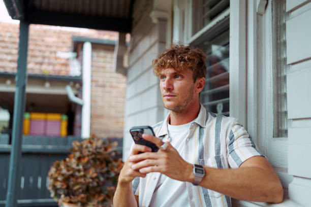 istock Young handsome man text messaging while sitting in front of his home 2196080394