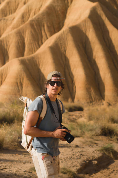 istock A traveler with a camera and backpack poses confidently amidst the dramatic sandstone formations of Bardenas Reales, embodying the spirit of exploration and discovery. 2196084106