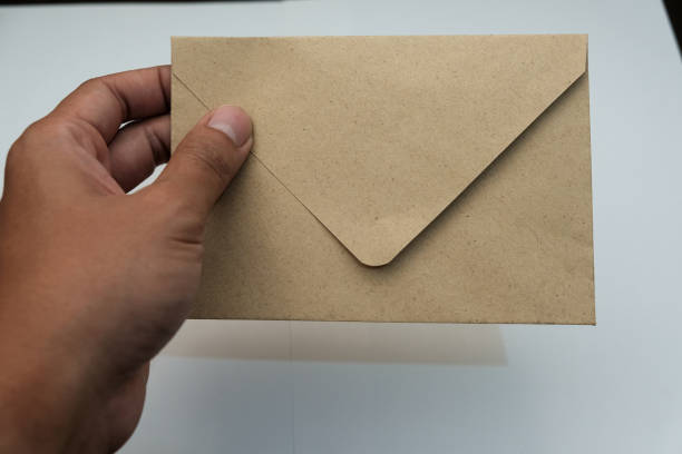 istock Closeup Male hands holding brown envelope isolated over white background 2196096739