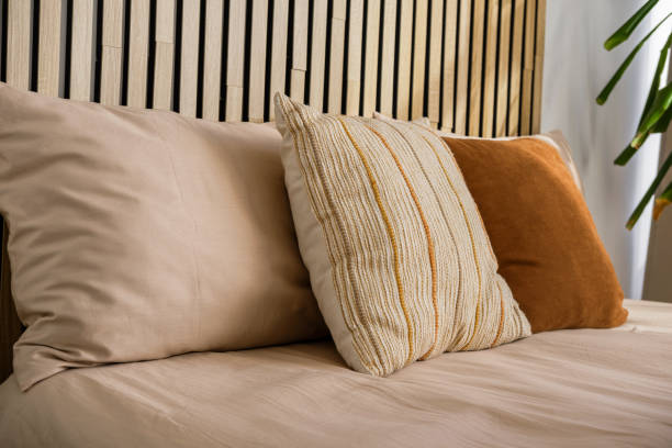 istock Cozy bedroom with decorative pillows and natural wood headboard 2196106633