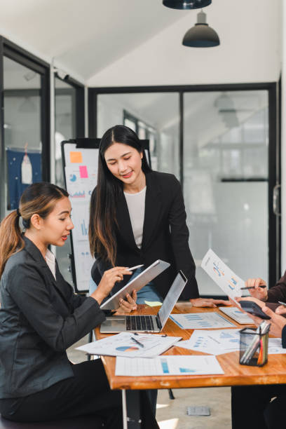 istock Professional women collaborating in modern office, discussing data and strategies while using tablet and laptop. Their focused expressions reflect teamwork and innovation 2196110257