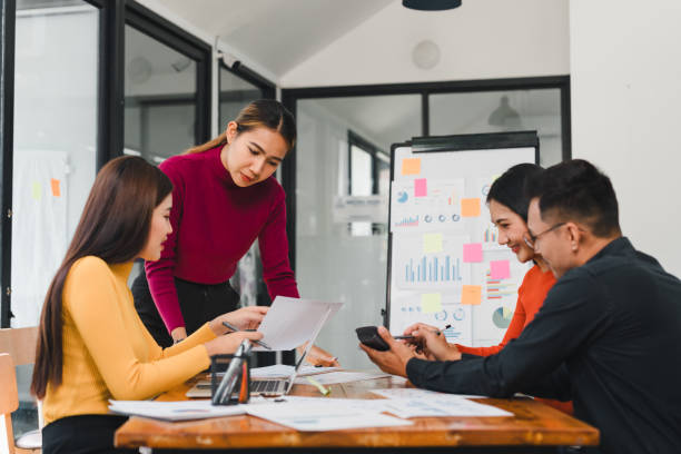 Collaborative business meeting with diverse professionals discussing ideas and analyzing data. Engaged teamwork in modern office setting fosters creativity and productivity