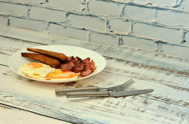 A plate of delicious and nutritious breakfast, scrambled eggs, crispy bacon and croutons on a wooden table. Close-up.