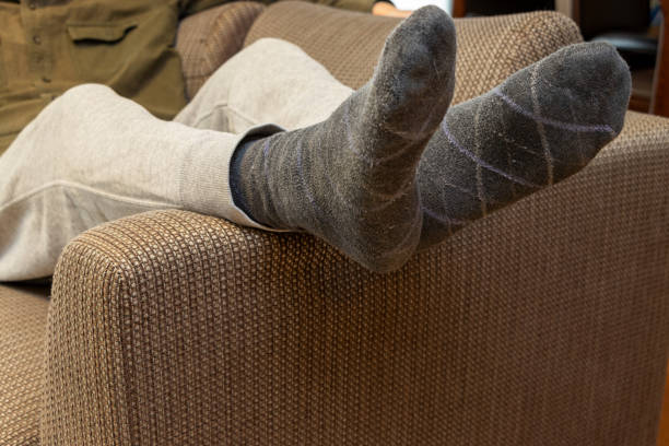 istock Man lying on sofa with feet up on armrest 2196118493