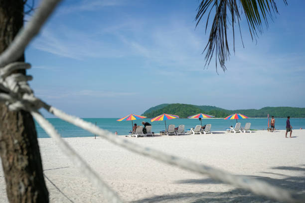 Langkawi, Malaysia - January 3, 2025: Tourists sunbathing at the beautiful beach of Pantai Cenang, one of the most popular beach spots in Langkawi.