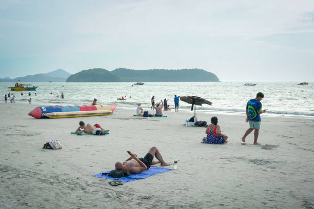Langkawi, Malaysia - January 3, 2025: Tourists relaxing at the beautiful beach of Pantai Cenang, one of the most popular beach spots in Langkawi.