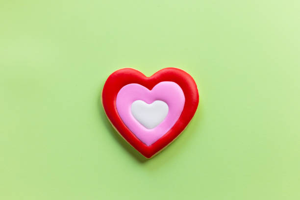 Handmade heart-shaped cookie with red, pink and white colors.