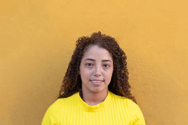 istock Young latin woman smiling and posing against yellow wall 2196123405