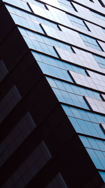 istock the sleek, reflective surface of a modern building, featuring sharp geometric lines and a minimalist aesthetic. The play of light on the glass panes creates a dynamic visual effect. 2196126103