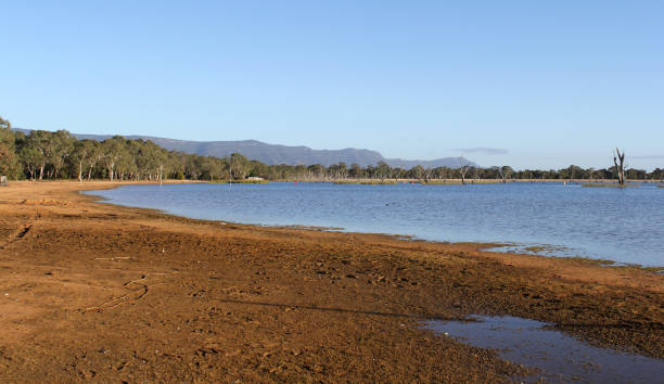 istock Calm lake of water with a sandy shoreline under a clear blue sky 2196126364