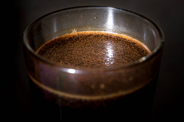 Close Up of coffee grounds floating on the surface of a glass cup