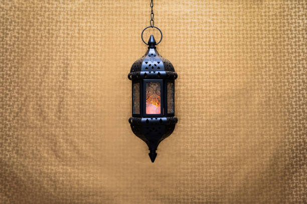 istock Black hanging lantern with light on golden background 2196129736