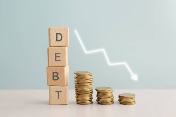 istock DEBT text on wooden background and stack of coins, down arrow for finance crisis, refinance, earnings management concept 2196129903