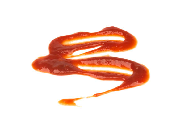Plastic bottle of ketchup or tomato sauce with fresh tomatoes on a red background.