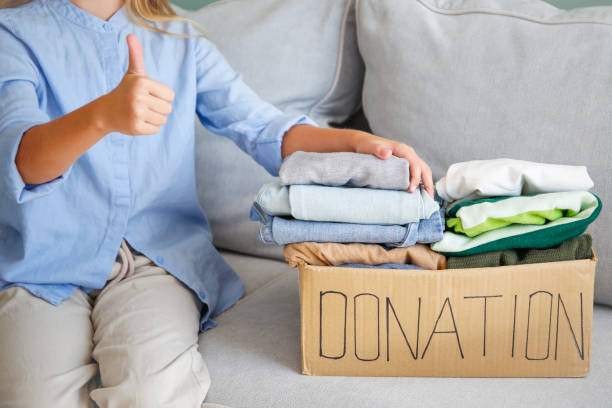 istock Girl holding donation box with with clothes. 2196131420