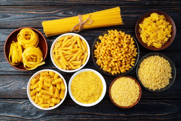 istock Assorted Uncooked Pasta in Bowls on Wooden Table 2196137872