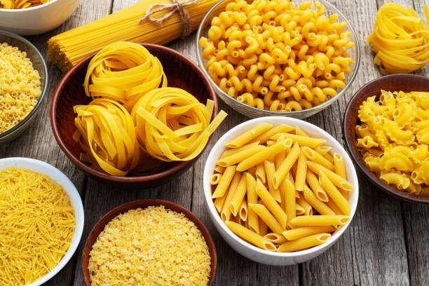 istock Assorted Uncooked Pasta in Bowls on Wooden Table 2196137876