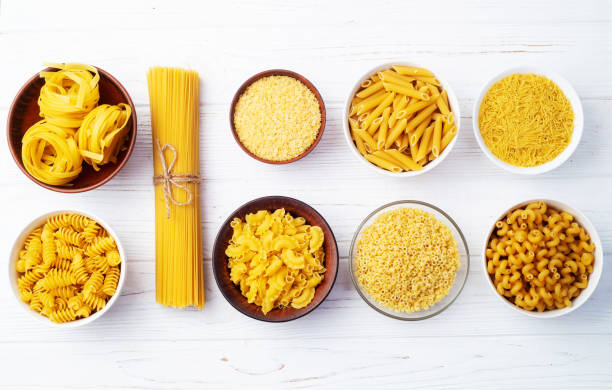 istock Assorted Uncooked Pasta in Bowls on Wooden Table 2196137879
