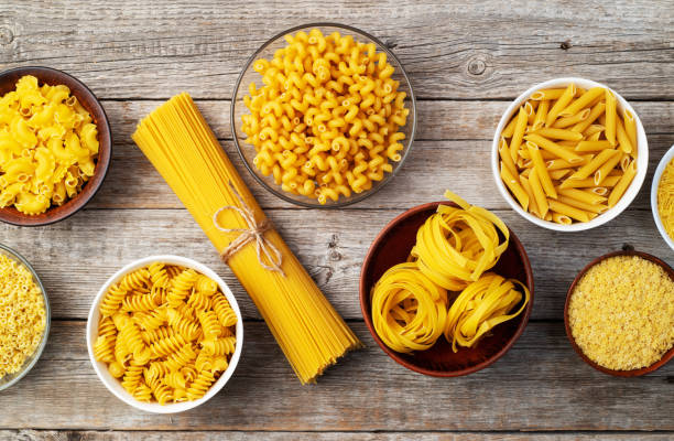 istock Assorted Uncooked Pasta in Bowls on Wooden Table 2196137885