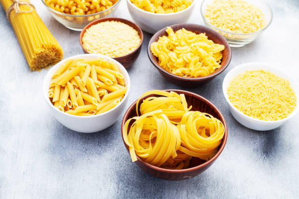 istock Assorted Uncooked Pasta in Bowls on Wooden Table 2196137901