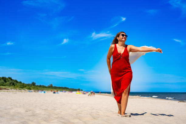 istock Smiling mature woman running on sandy beach 2196141208