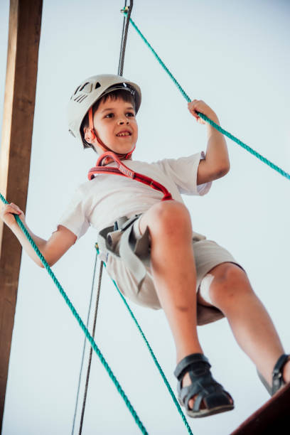 istock Boy in helmet doing rock climbing in rope park walking on ropeway overcoming obstacles 2196141688