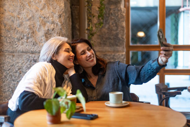 istock Two smiling women taking a selfie in a cafe 2196142963