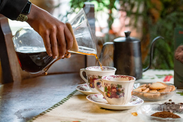 istock Pour over filter coffee alternative brewing method. Girl is pouring hot water over roasted and ground coffee beans contained in paper filter 2196144426