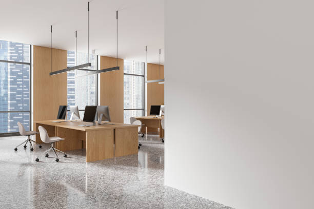 istock Modern open-plan office interior with wooden desks and computer setups, surrounded by large windows overlooking skyscrapers. 3D Rendering 2196144462